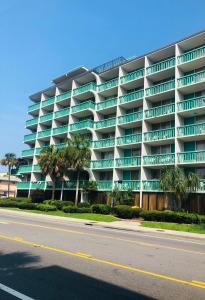 a large apartment building with palm trees in front of a street at Quail Inn and Suites - Myrtle Beach in Myrtle Beach
