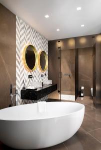 a bathroom with a large white tub and two mirrors at Lure Hotel & Spa - Adults Only in Mellieħa