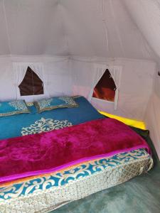 ein Bett in einem Zelt mit einer lila Decke in der Unterkunft TRIBE AQUA a nature retreat above Neer waterfall in Rishikesh