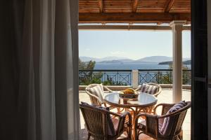 a table and chairs on a balcony with a view of the ocean at Villa Angelo in Kassiopi