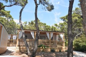 une maison entourée d'une terrasse couverte avec des arbres dans l'établissement Mobile Homes Sara - Camping Baško Polje , Adriatic , Dalmatia, à Baška Voda