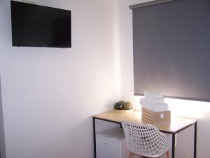 Zimmer mit einem Schreibtisch und einem TV an der Wand in der Unterkunft Albergue San Pedro in Corcubión