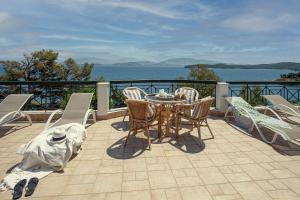 a table and chairs on a balcony with a view of the water at Villa Angelo in Kassiopi