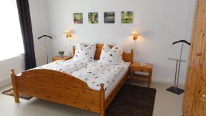 1 dormitorio con cama de madera con sábanas y almohadas blancas en FeWo Obstfelderschmiede, en Mellenbach-Glasbach