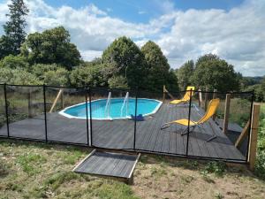a fence around a swimming pool with a deck and chairs at Gite de puy faucher in Arrènes