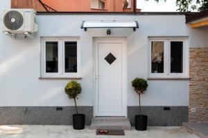 ein weißes Haus mit einer weißen Tür und zwei Topfpflanzen in der Unterkunft Apartman Noel Peroj centar in Peroj