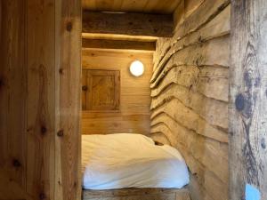 a bed in a wooden room with a stone wall at Chateau Paysan ecolobio de Durianne in Le Monteil