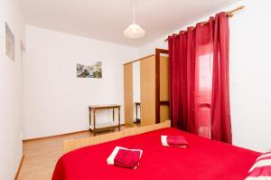a bedroom with a red bed with red curtains at Guest House Kola in Slano