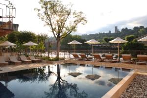 una piscina en un hotel con sillas y sombrillas en Corte Regia Relais & Spa, en Valeggio sul Mincio