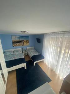 a bedroom with two beds and a blue wall at Pod Dębem in Międzyzdroje