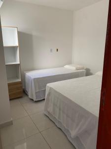 1 dormitorio con 2 camas y estante para libros en Mellim Residence en Maragogi