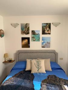 a bedroom with a blue bed with pictures on the wall at Casa Ilaria - Appartamento in Piazzetta in Capri