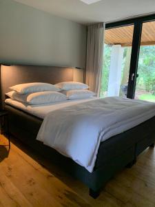 a bedroom with a large bed with white sheets and pillows at Bungalow im Wald in Borkwalde