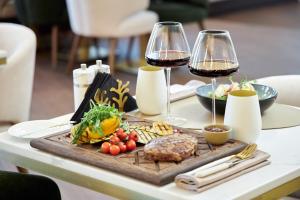 una mesa con dos copas de vino y una bandeja de comida en River Palace Hotel, en San Petersburgo