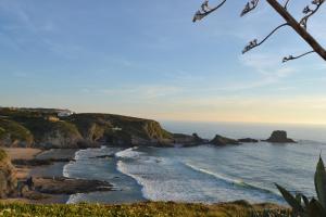 a view of a beach with rocks and the ocean at Casa Alentejana in São Teotónio
