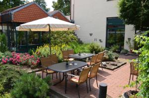 eine Terrasse mit Tischen, Stühlen und einem Sonnenschirm in der Unterkunft velcrea in Willebadessen