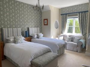 a bedroom with two beds and a chair and a window at Burleigh House B and B in Tenbury +25 photos