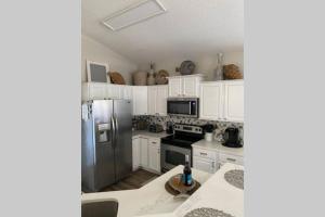 a kitchen with white cabinets and a stainless steel refrigerator at Beach Jewel 5bd-3 1/2 bath -5 min walk to Beach! in Destin