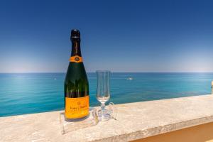a bottle of wine and a glass on a ledge with the ocean at Taliammari in Cefalù