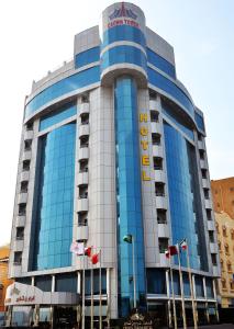 um edifício azul alto com bandeiras à frente em Crown Tower Hotel em Al Jubail