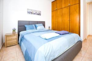 a bedroom with a large bed with blue sheets and a wooden cabinet at MyNapa Apartments in Ayia Napa