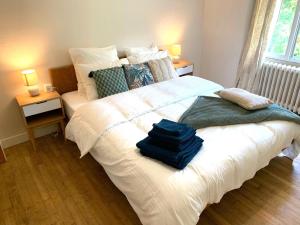 - une chambre avec un grand lit blanc et des serviettes dans l'établissement Villa au bord de la Rivière avec Jacuzzi, à Ségur-le-Château