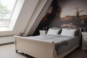 a bedroom with a bed with a painting of a windmill at B&B Schotererf in Kuinre