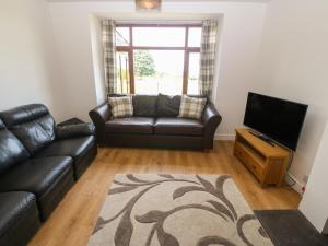 a living room with a leather couch and a flat screen tv at Y Berth Ddu Farmhouse in Caernarfon