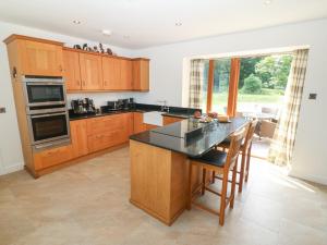 a kitchen with wooden cabinets and a table with chairs at Y Berth Ddu Farmhouse in Caernarfon