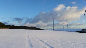 um campo coberto de neve com turbinas eólicas ao fundo em Kehrmühle em Ober Kostenz