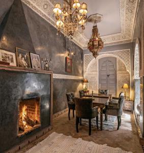 a living room with a fireplace and a table and chairs at Riad Zhor in Marrakesh