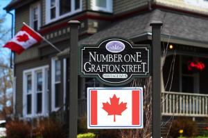 una señal frente a una casa con bandera canadiense en No 1 Grafton Inn en Charlottetown