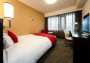 ein Hotelzimmer mit einem Bett, einem Schreibtisch und einem TV in der Unterkunft Daiwa Roynet Hotel Okayama Ekimae in Okayama