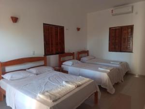 a room with two beds and two windows at Amazônia Kite Club in Luis Correia