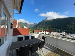 a balcony with a wooden table and chairs and mountains at Balestrand Fjordapartments in Balestrand