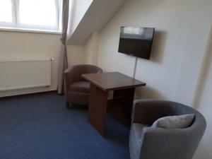 a room with a table and two chairs and a television at Penzion a wellness - JILAN, Náves Svobody 39, Olomouc in Olomouc