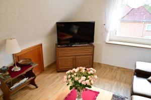 a living room with a television and a vase of flowers at Haus Lisa Burg Dithmarschen am Nord Ostsee Kanal Nordsee in Burgerfeld