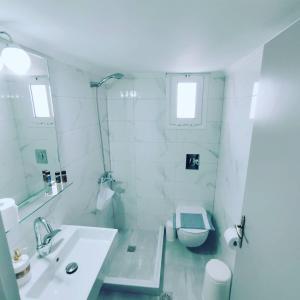 uma casa de banho branca com um lavatório e um WC em VASO'S APARTMENTS em Tolo