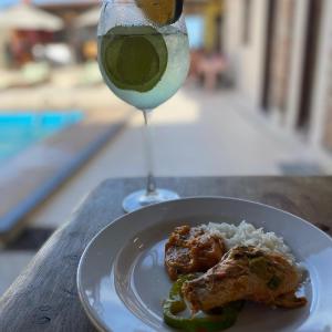 a plate of food with rice and a glass of wine at Pousada e Restaurante Sol e Lua in Mucuri