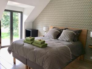 1 dormitorio con 1 cama con toallas verdes en Aux Bois Dorés de la Ferme de sorval, animaux de la ferme, fitness, en Selvigny