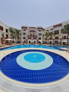 Lovely Apartment in Jebel Sifah with private Garden - As sifah في مسقط: حمام سباحة أزرق كبير مع مباني في الخلفية