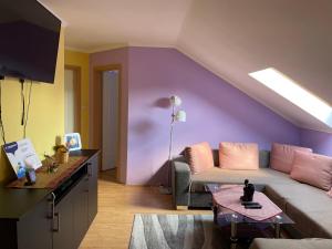 een woonkamer met een bank en een paarse muur bij Julius Apartman in Hajdúszoboszló