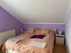 1 dormitorio con 1 cama grande y paredes moradas en Julius Apartman, en Hajdúszoboszló