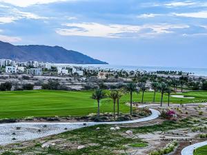 um campo de golfe com palmeiras e o oceano em Lovely Apartment in Jebel Sifah with private Garden - As sifah em Mascate