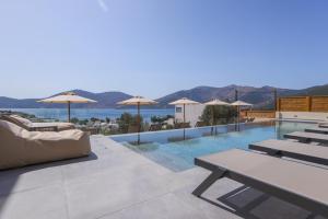 a swimming pool with tables and umbrellas on a building at Elivia Boutique Suites in Almiropótamos