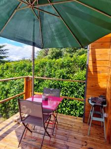 una mesa y sillas en una terraza con sombrilla en Lodge avec vue panoramique, en Saint-Sorlin