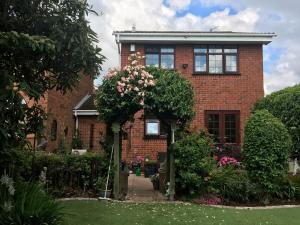 een rood bakstenen huis met een tuin ervoor bij Jen's Friendly Place in Dudley