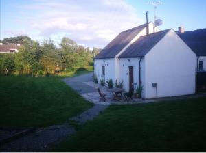 a small white house with a picnic table in a yard at Bluebell Cottage - with hottub in Newry