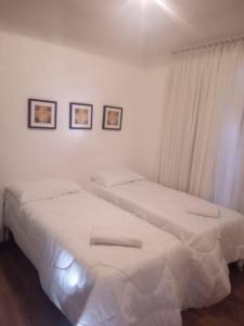 Duas camas num quarto com paredes brancas em Resort com Natureza no Centro em Gramado