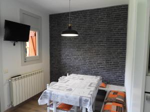 een eetkamer met een witte tafel en een bakstenen muur bij Bassiero Apartament in Esterri d'Àneu
